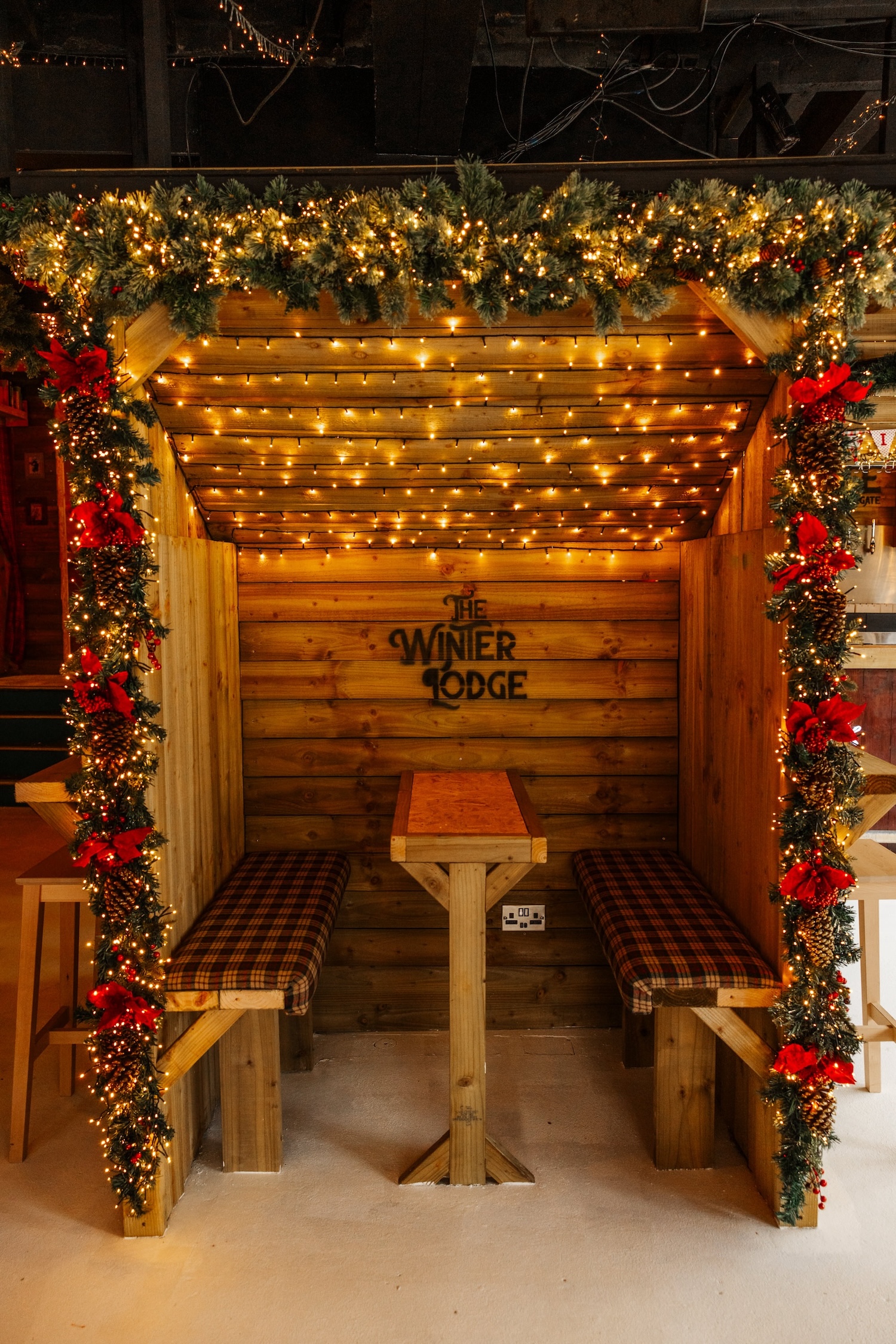 A cosy garlanded hut booth with tartan seats